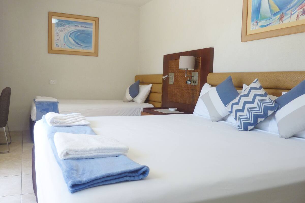 Habitación de hotel con dos camas, televisión, un cuadro y una lámpara.