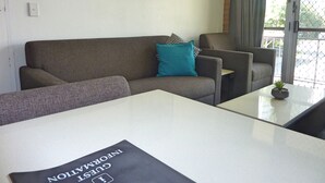 Una sala moderna con un sofá gris, un sillón a juego y una pequeña mesa con una planta en maceta.