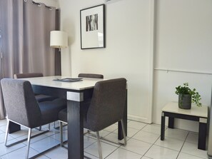 A modern dining area with a table, chairs, a lamp, a framed picture, and a small plant on a side table.
