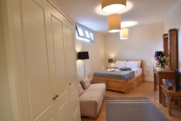 A bedroom with a bed, a sofa, a desk, and a wardrobe. - Brighter Properties (London)