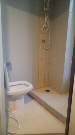 A small, enclosed shower stall with a toilet and a showerhead.