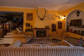 A living room with striped sofas, a fireplace, and a mounted deer head. - Quinta de Rio Alcaide (Porto de Mos)