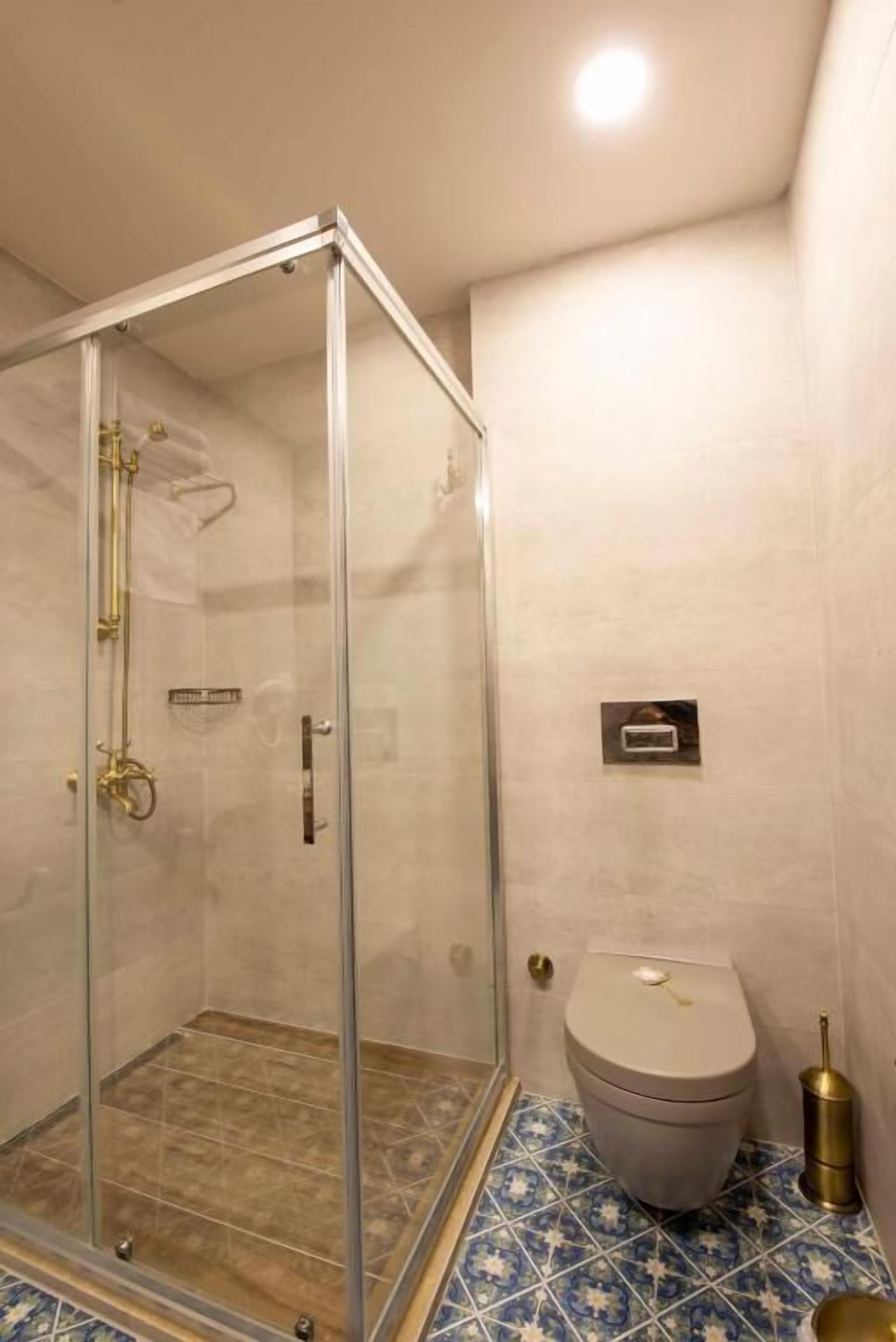 A bathroom with a glass shower enclosure, a toilet, and a bidet.