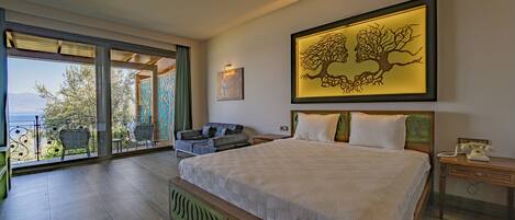 A bedroom with a large bed, a view through a glass door, a framed artwork, and a nightstand with a phone.