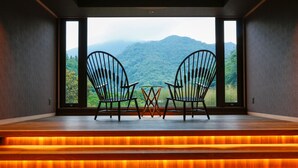 A room with two chairs facing a large window overlooking a mountainous landscape. - Asan Kotonami (Manno)