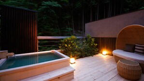A wooden deck with a hot tub, wicker furniture, and a small illuminated lamp. - Asan Kotonami (Manno)