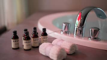 A bathroom sink with a mirror, a faucet, and four bottles of Arga shampoo and conditioner.