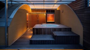 Et område med jacuzzi, trætrin og en overdækket gang.