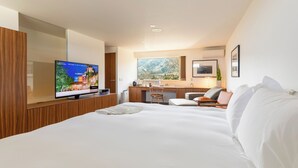Et moderne hotelværelse med en stor seng, et fjernsyn, et skrivebord og et vindue med udsigt over landskabet.