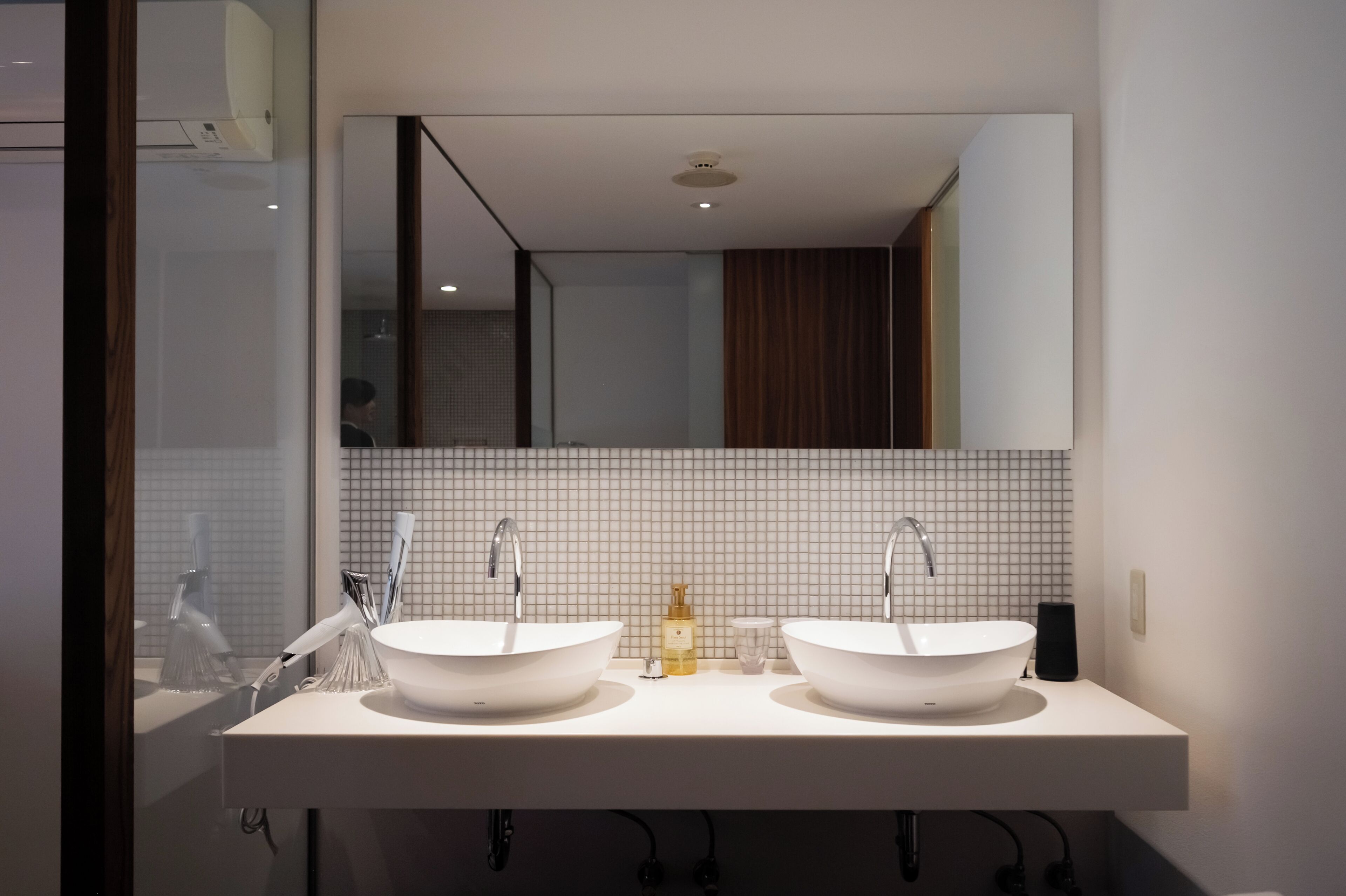Un baño moderno con dos lavamanos, un espejo grande y un salpicadero de azulejos.