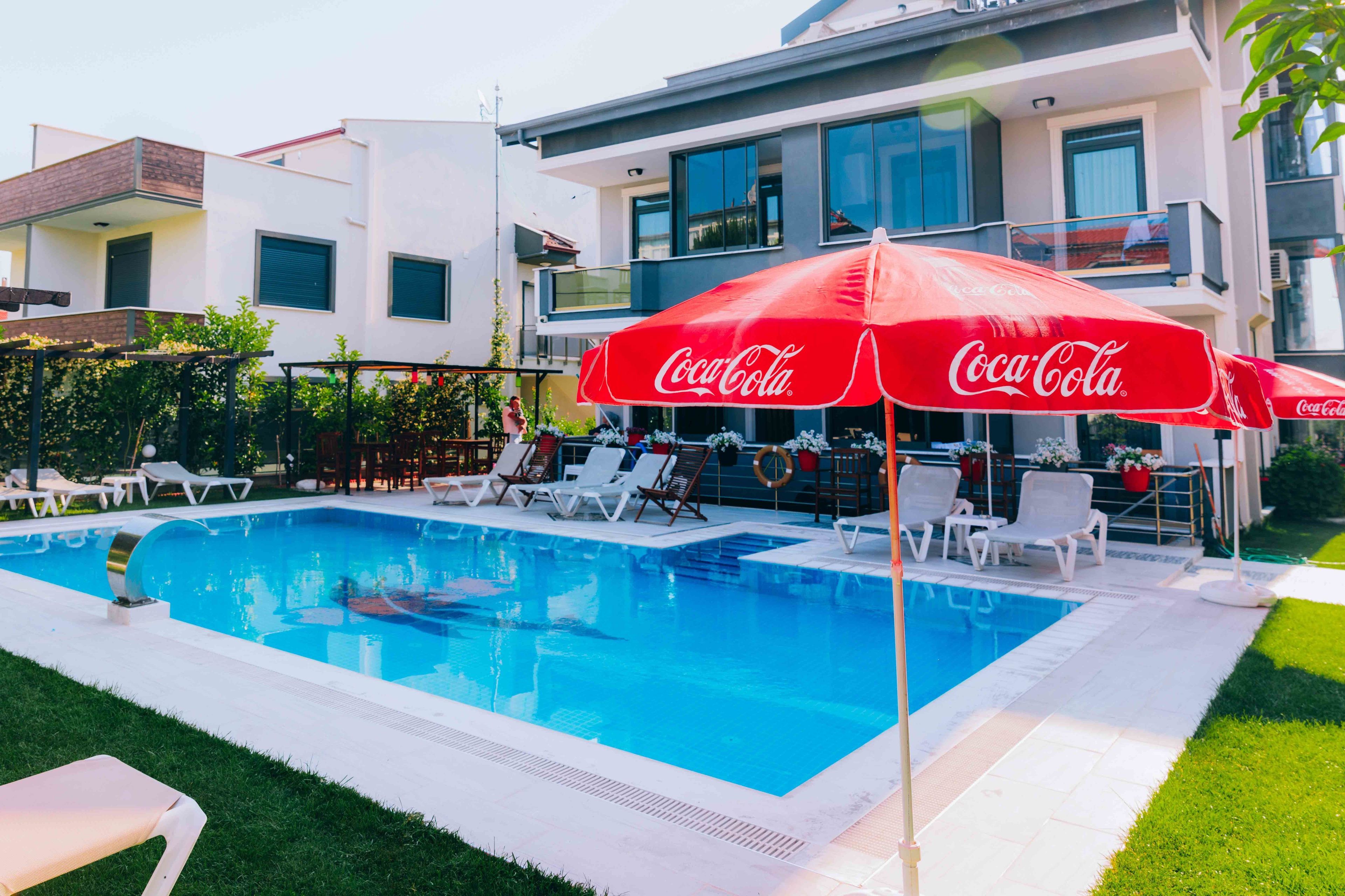 Uima-allas, jossa on aurinkotuoleja ja Coca-Colan logolla varustettu aurinkovarjo.