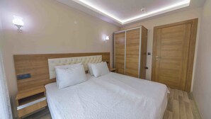 A bedroom with a bed, wooden wardrobe, and built-in nightstands. - Asil Apart Otel (Burhaniye)