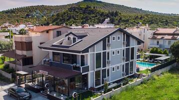 A modern two-story house with a flat roof, large windows, and a small balcony.