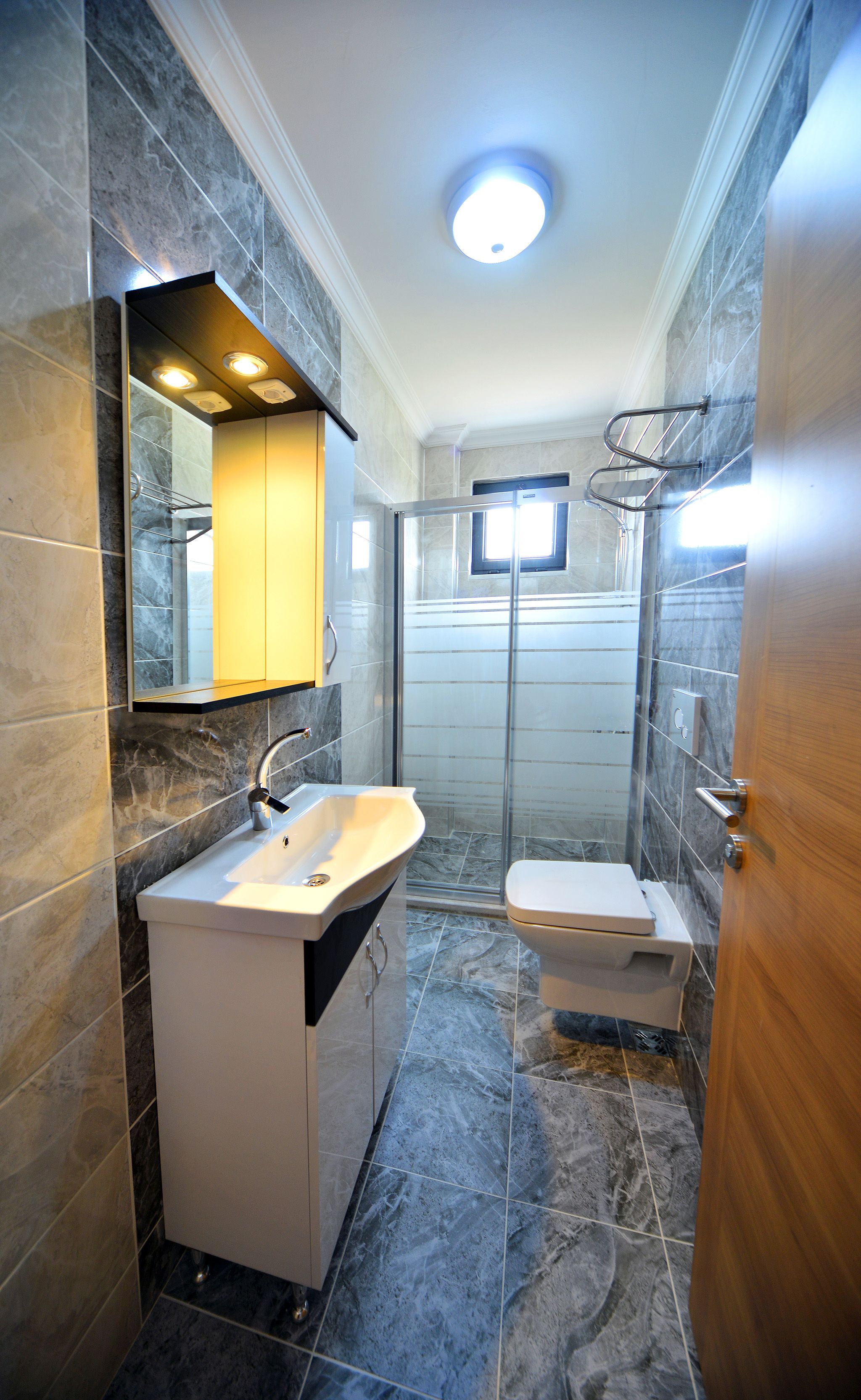 A modern bathroom with a marble sink, a toilet, and a glass shower enclosure.