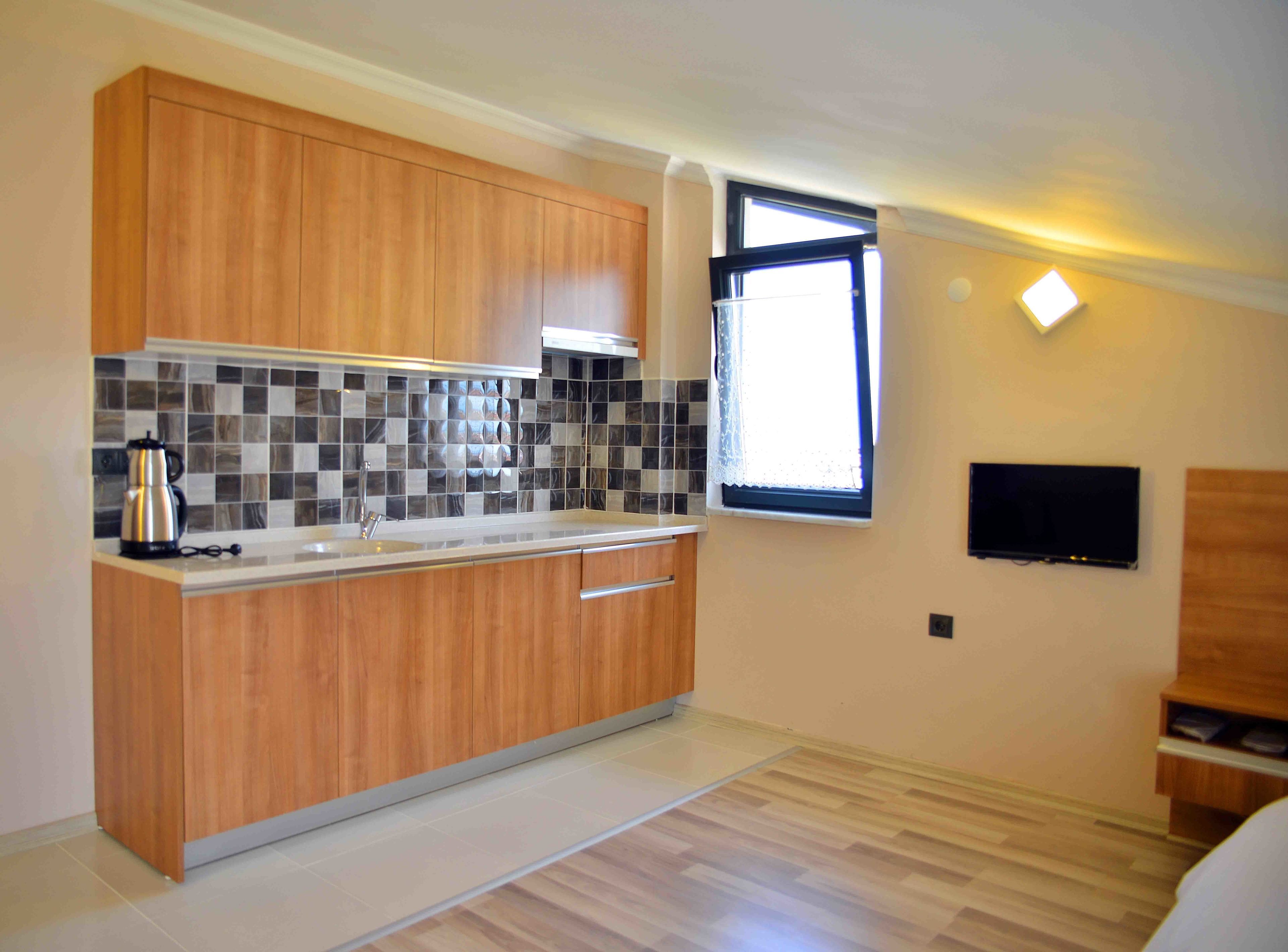 Una cocina moderna con armarios de madera, un salpicadero de azulejos, un ventanal con vistas y un televisor de pantalla plana montado en la pared.