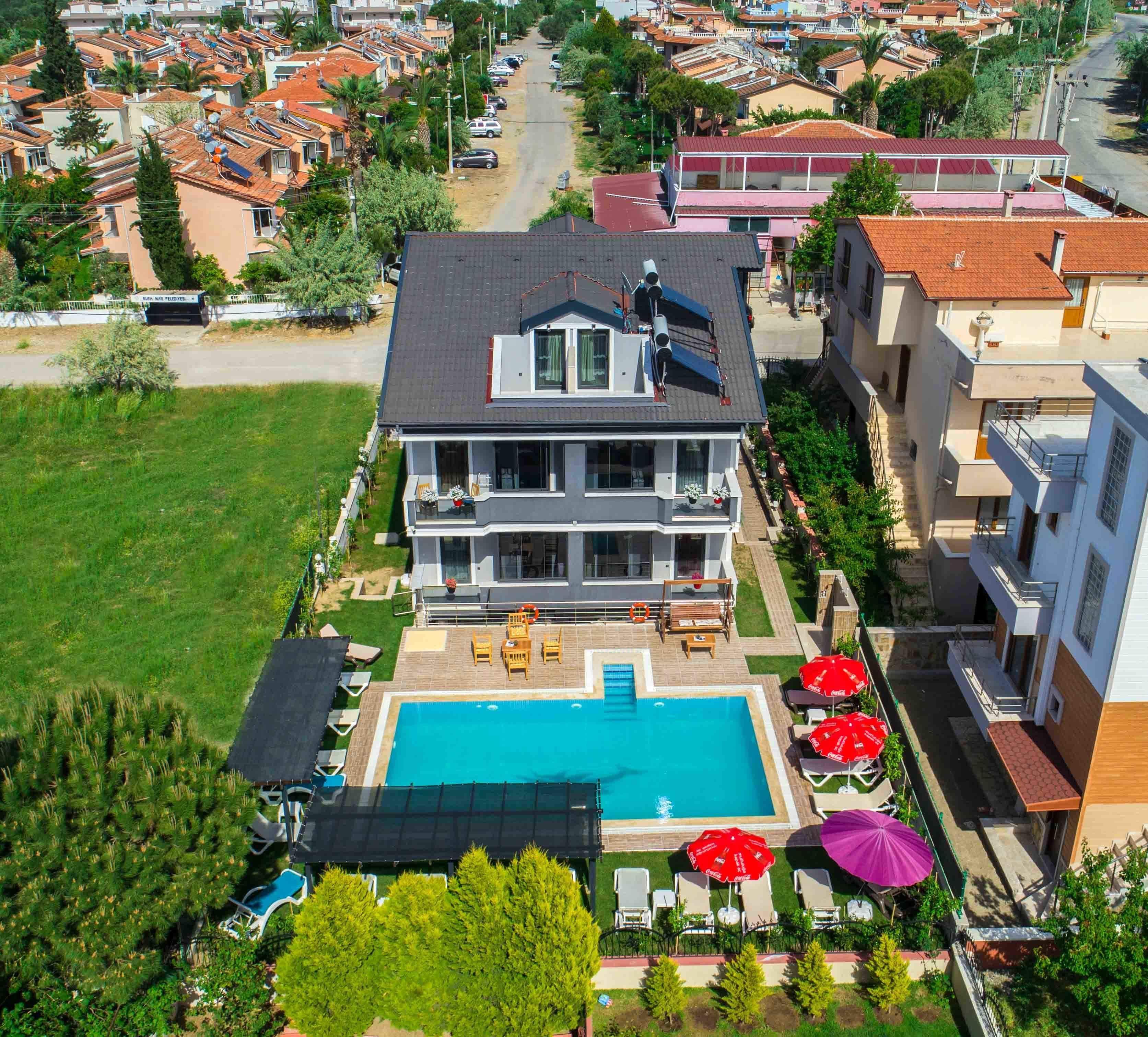 A two-story house with a swimming pool, outdoor furniture, and a garden.