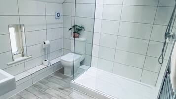 Un baño moderno con cabina de ducha de vidrio, inodoro y lavamanos.