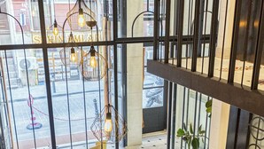 A lobby with a high ceiling, a yellow armchair, a small table, and a potted plant. - Taksim Avenue Hotel (Istanbul)