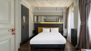A hotel room with a large bed, a dark headboard, a mirror above the bed, a radiator, and a door with a no-smoking sign. - Taksim Avenue Hotel (Istanbul)