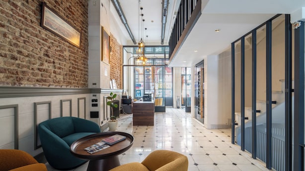 A hotel lobby with a brick wall, a reception desk, and a seating area with chairs and a table. - Taksim Avenue Hotel (Istanbul)