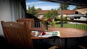 Una terraza de madera con una mesa, sillas, un florero y un periódico.
