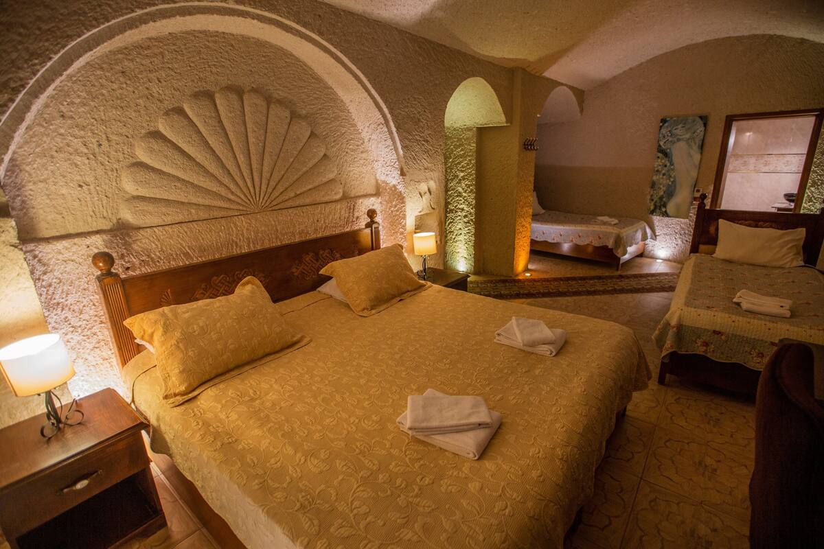 A hotel room with a large bed, a smaller bed, a nightstand, and a lamp.