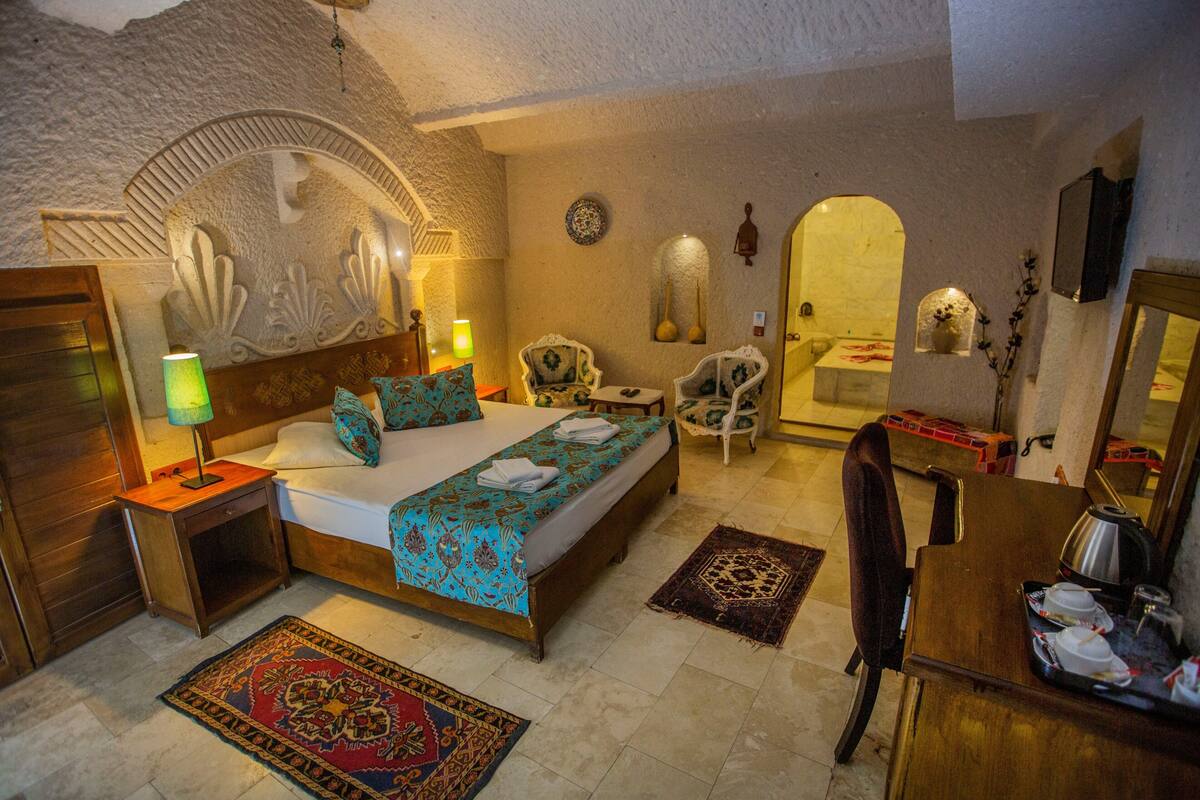 A bedroom with a bed, bedside tables, a chair, a desk, and a mirror.