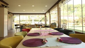 Un comedor amplio con una mesa larga, múltiples sillas y grandes ventanales que ofrecen vistas al exterior.