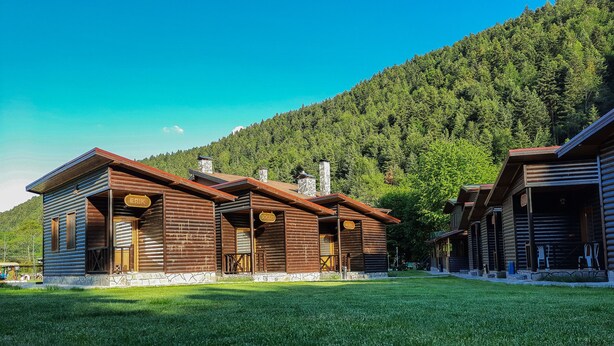 Un hotel tipo cabaña de madera con varias habitaciones, cada una con una señalización de nombre distintiva.
