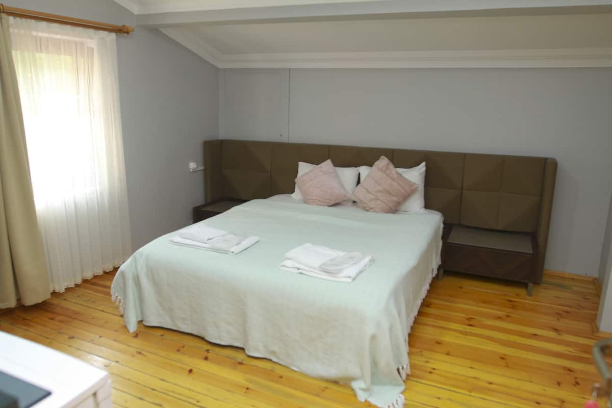 A bedroom with a bed, wooden floor, and a headboard.