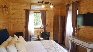 Una habitación de cabaña de madera con una cama, un escritorio, una silla y un televisor.