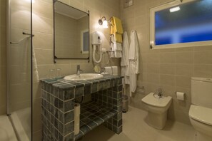 Un baño con lavamanos, espejo, toallero y retrete.