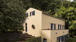Un edificio moderno de dos pisos con un muro de piedra y un pequeño jardín.