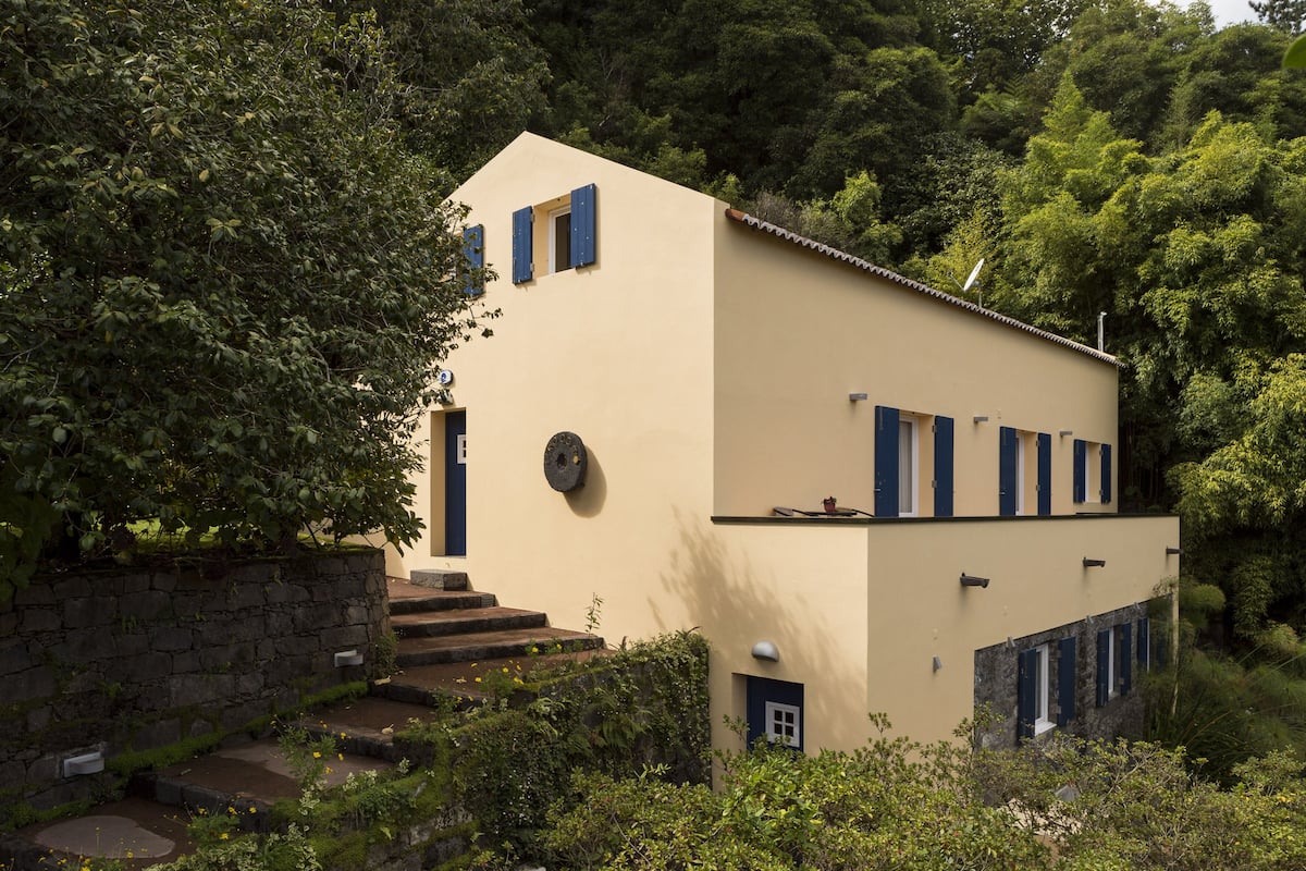 A modern two-story building with a stone wall and steps leading to the entrance.