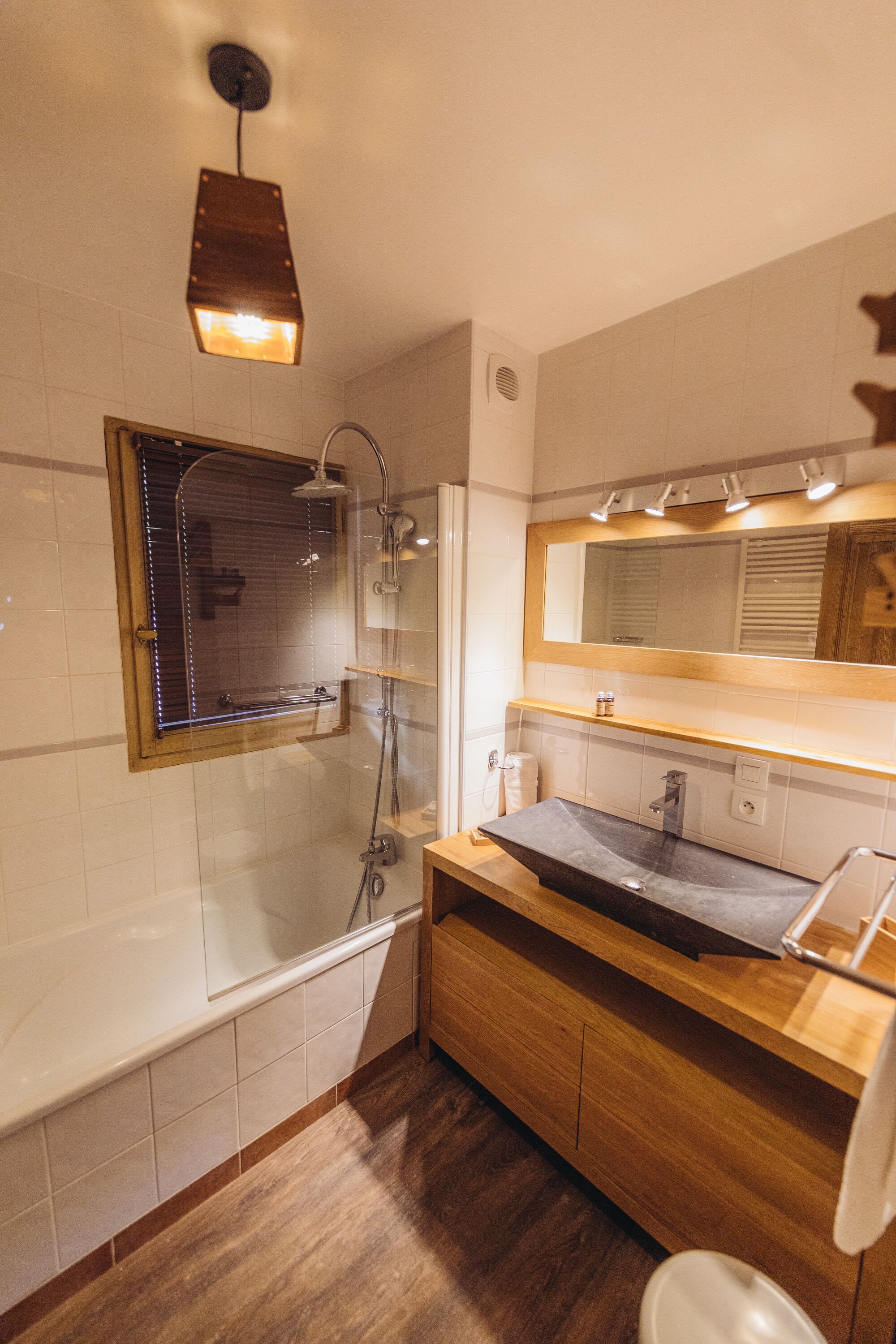 A modern bathroom with a wooden vanity, a large mirror, a shower, and a bathtub.
