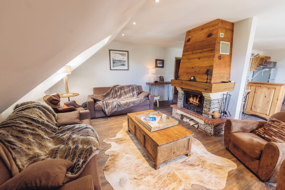 A cozy living room with a fireplace, leather sofas, and a wooden coffee table.