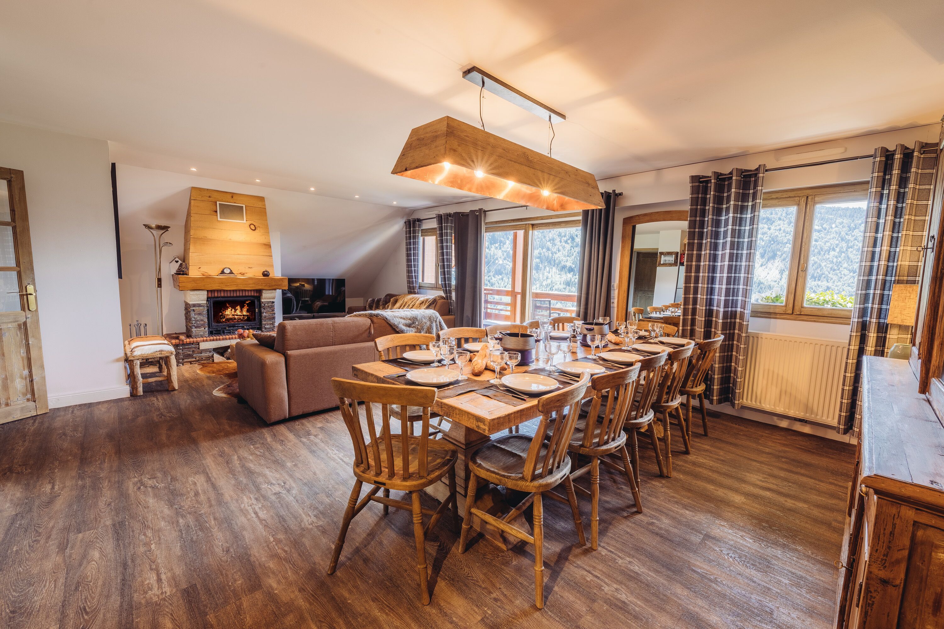 A spacious living area with a high ceiling, a fireplace, and a dining table set for six.