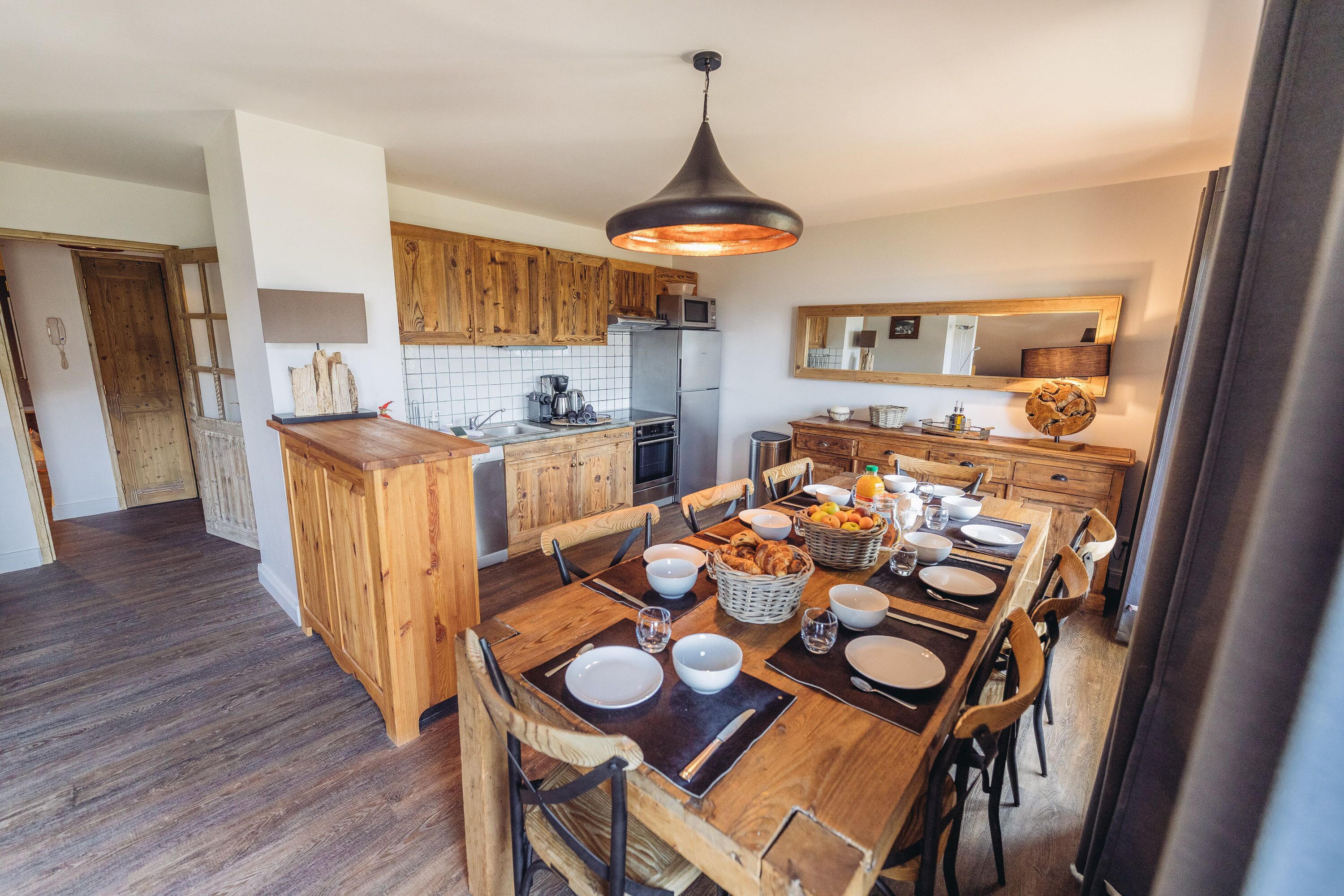 A modern kitchen with wooden cabinets, a central island, and a dining area set for six.