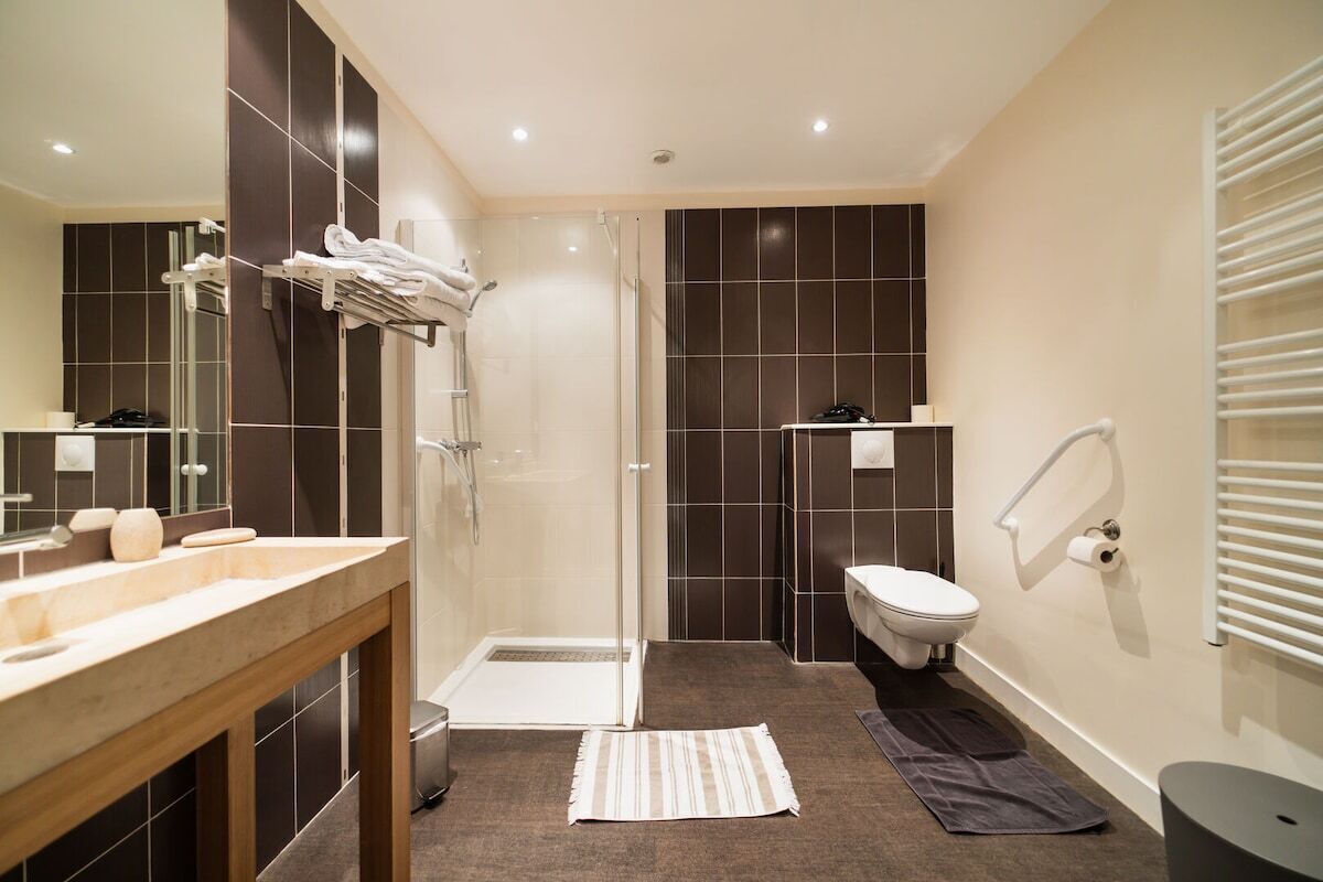 Een moderne badkamer met een douchecabine van glas, een wit toilet en een wastafel met spiegel.