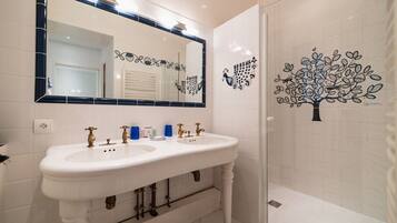 Une salle de bain avec deux lavabos, un grand miroir et des œuvres d’art décoratives au mur.