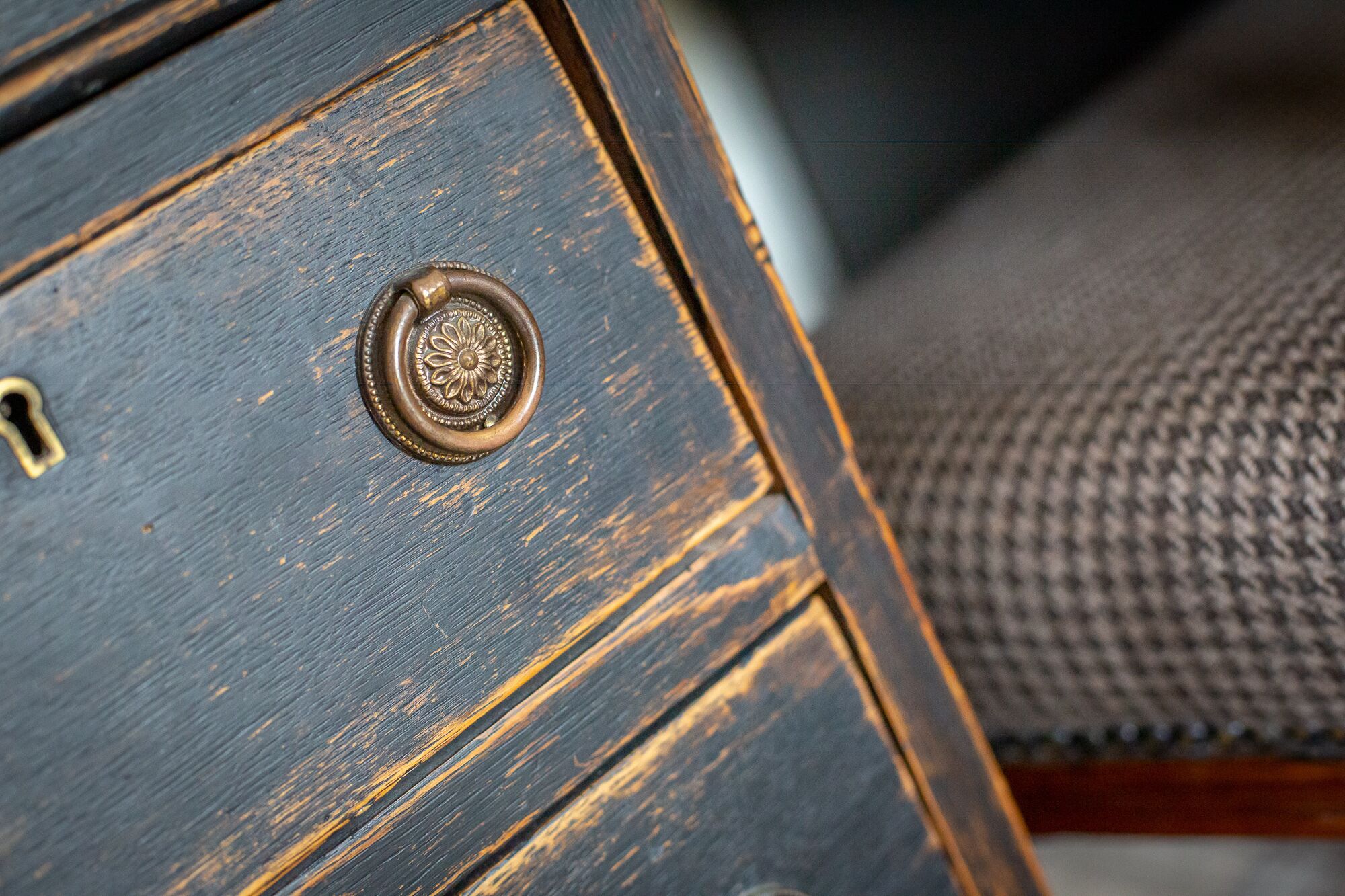 A close-up of a wooden drawer with a brass handle and a keyhole.
