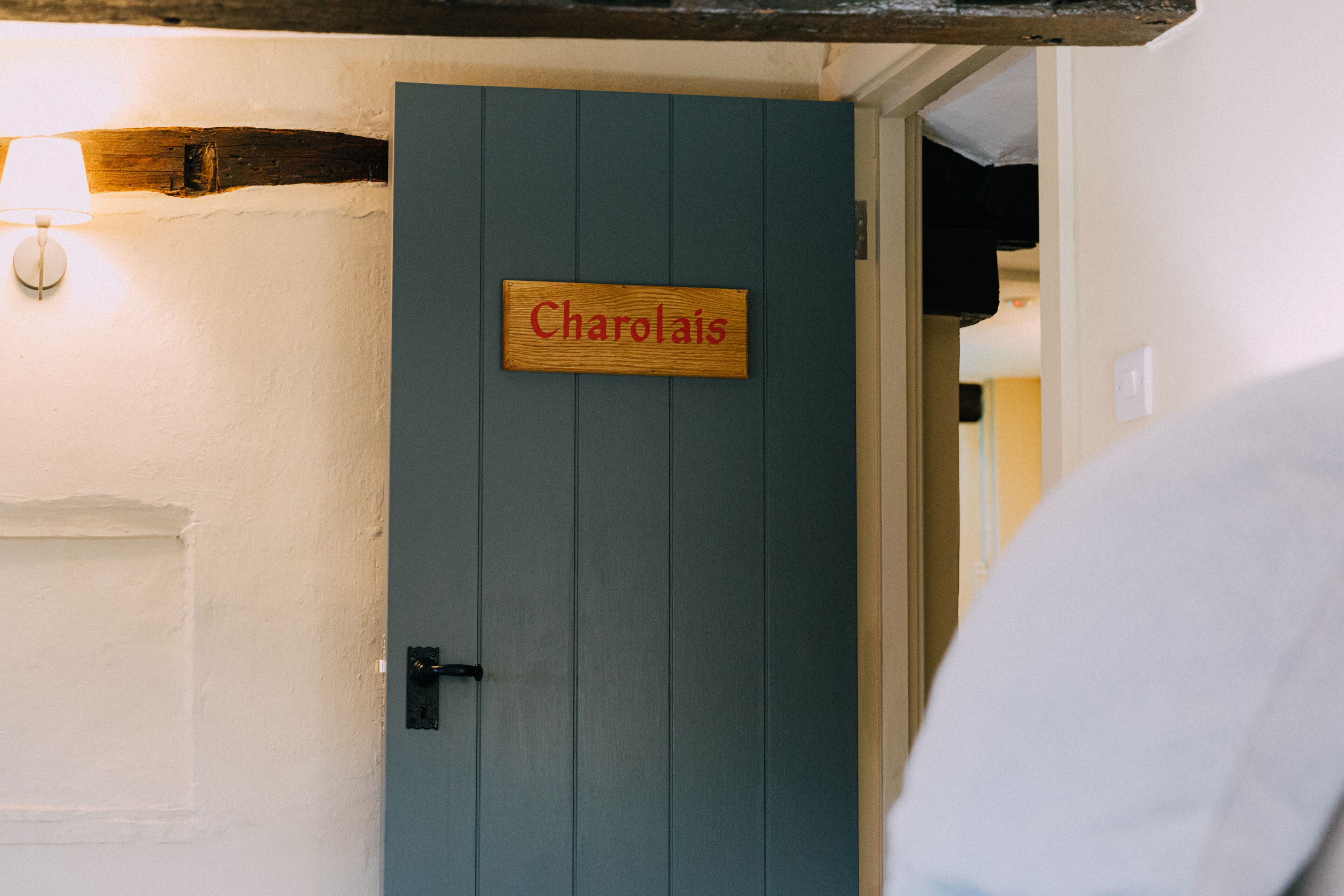 Eine Tür mit einem Schild, auf dem "Charolais" steht, und einer Wandleuchte links.
