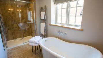 A modern bathroom with a glass-enclosed shower, a freestanding bathtub, and a window providing natural light.