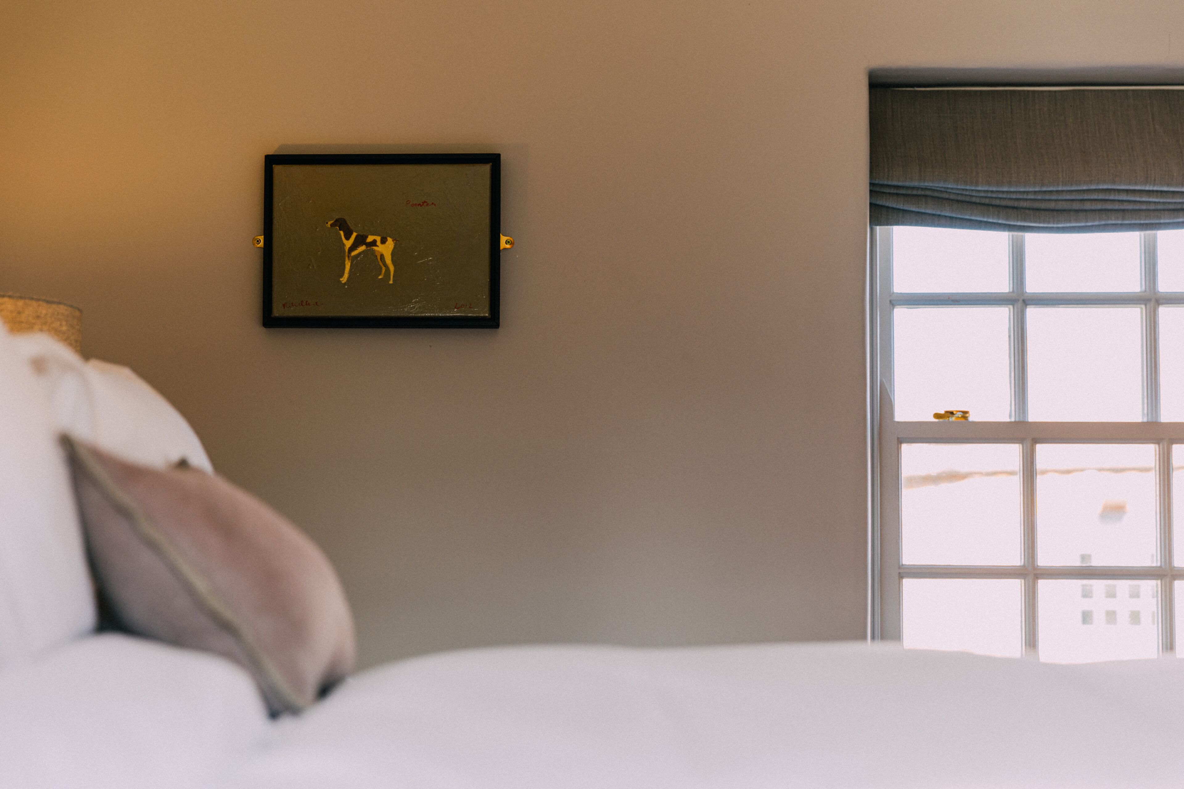 Ein Schlafzimmer mit einem Bett, einem gerahmten Bild an der Wand und einem Fenster mit Blick.