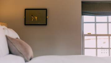 Ein Schlafzimmer mit einem Bett, einem gerahmten Bild an der Wand und einem Fenster mit Blick.