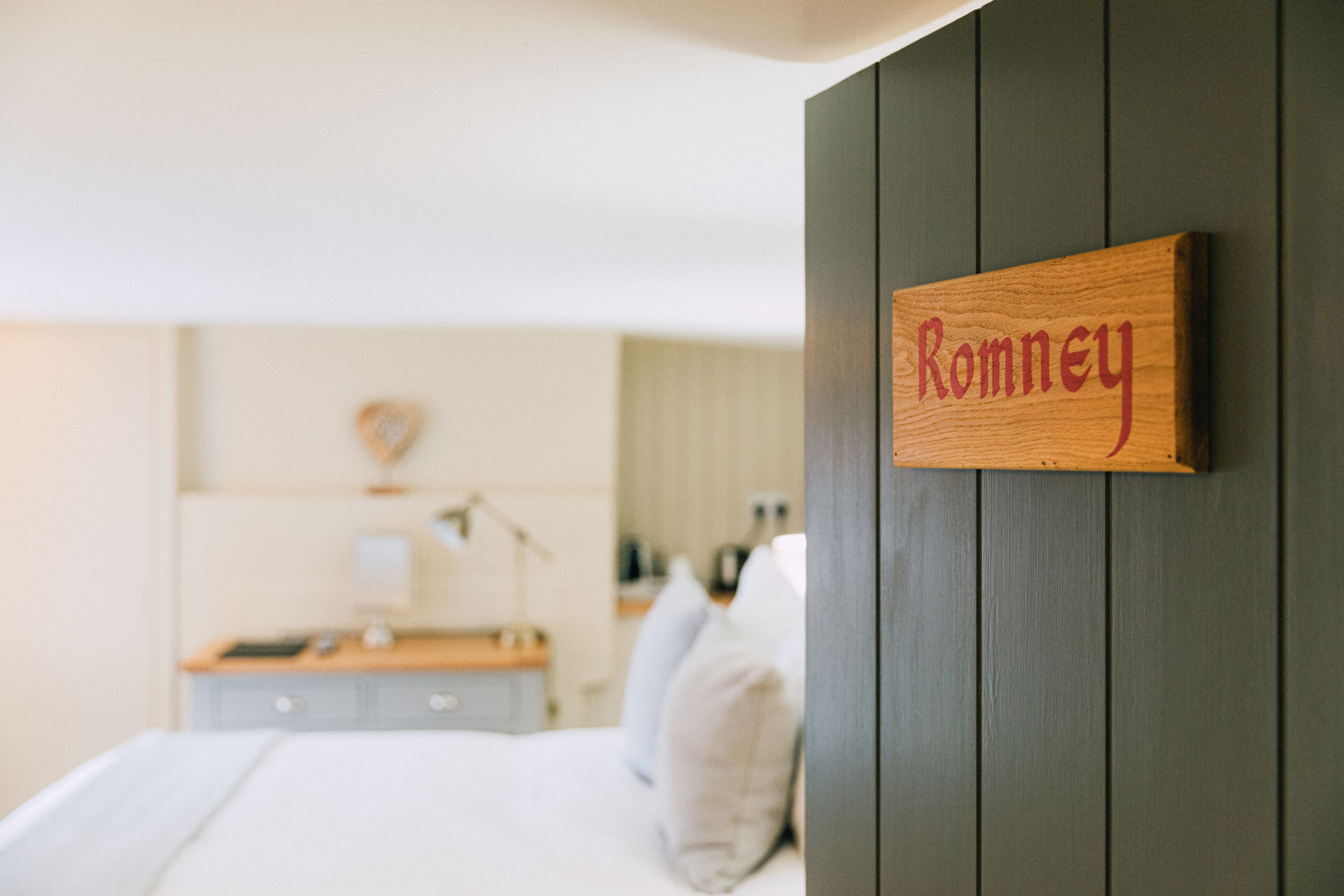 Un dormitorio con un letrero de madera en la pared que dice 'Romney'.