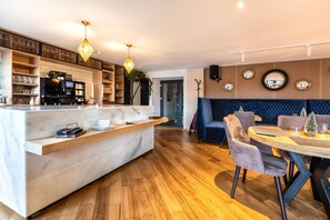 A modern hotel lobby with a reception desk, seating area, and a dining space.