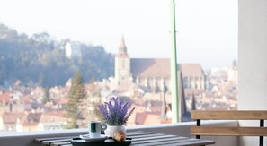 A balcony with a table, a cup, a pastry, and a potted lavender plant.