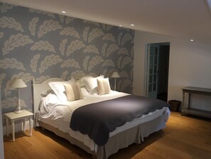 A neatly made bed with a dark throw blanket, two bedside lamps, and a patterned wallpaper. - La Girarde (Saint-Quentin-de-Caplong)