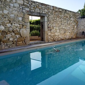Una piscina al aire libre, sombrillas, sillones reclinables de piscina